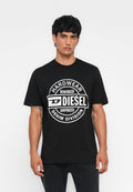 Mann trägt ein schwarzes Diesel-T-Shirt mit großem weißem rundem Logo und dem Text "HARDWEAR DENIM DIVISION" auf einem einfarbigen Hintergrund.