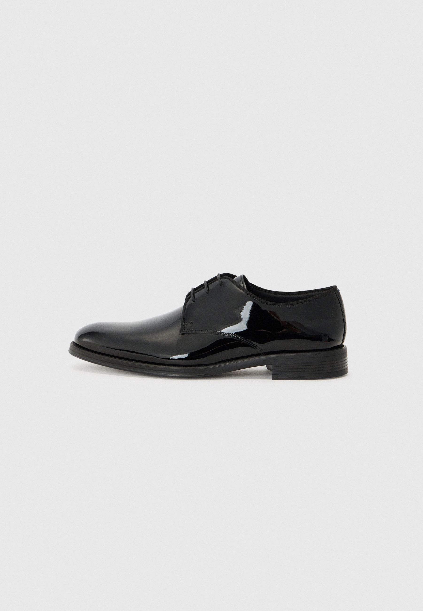 Schwarze Dressschuhe mit einem glänzenden Lackleder-Finish, runder Zehenform und externen Nähten. Sie verfügen über einen niedrigen Absatz und eine Schnürung.