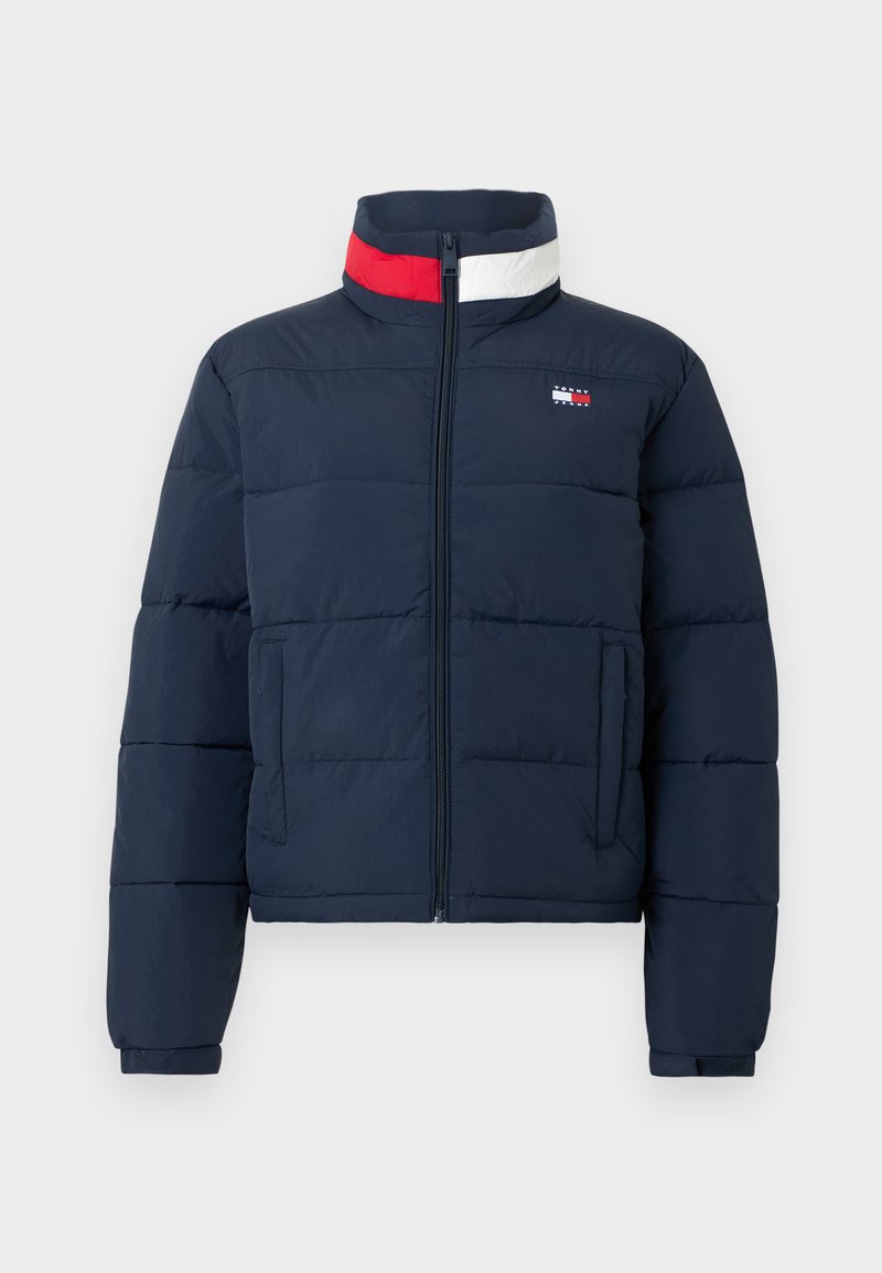 Marineblaue Steppjacke mit hohem Kragen, Frontreißverschluss und zwei Seitentaschen. Mit roten und weißen Akzentstreifen am Kragen.