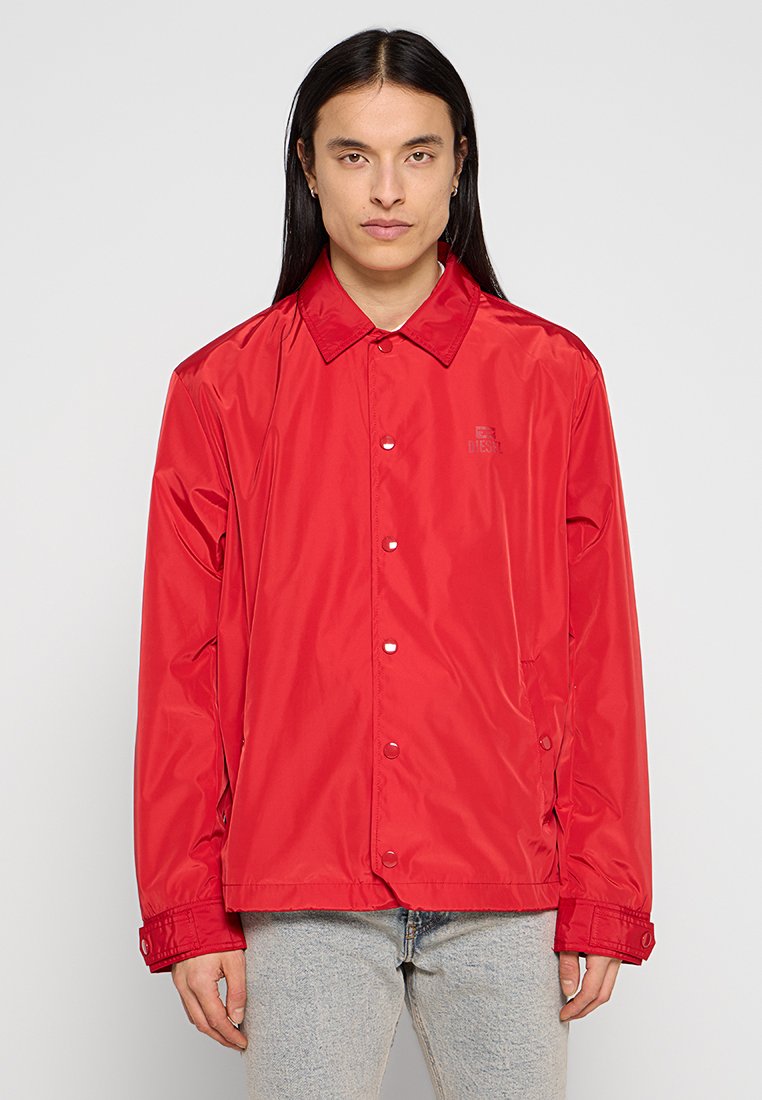 Rote, leichte, wasserdichte Jacke mit Kragen, Druckknöpfen und einem kleinen Logo auf der Brust. Sie hat lange Ärmel und einen lässigen Schnitt.
