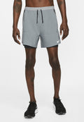 Graue Sportshorts mit einem Kordelzugbund, seitlichen Taschen und schwarzem Innenfutter, kombiniert mit schwarzen Laufschuhen mit weißen Akzenten.
