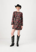 Blumenmuster-Kleid in Dunkelbraun mit langen Ärmeln, kombiniert mit schwarzen Cowboy-Stiefeln mit silberner Stickerei und einem schwarzen Cowboyhut.