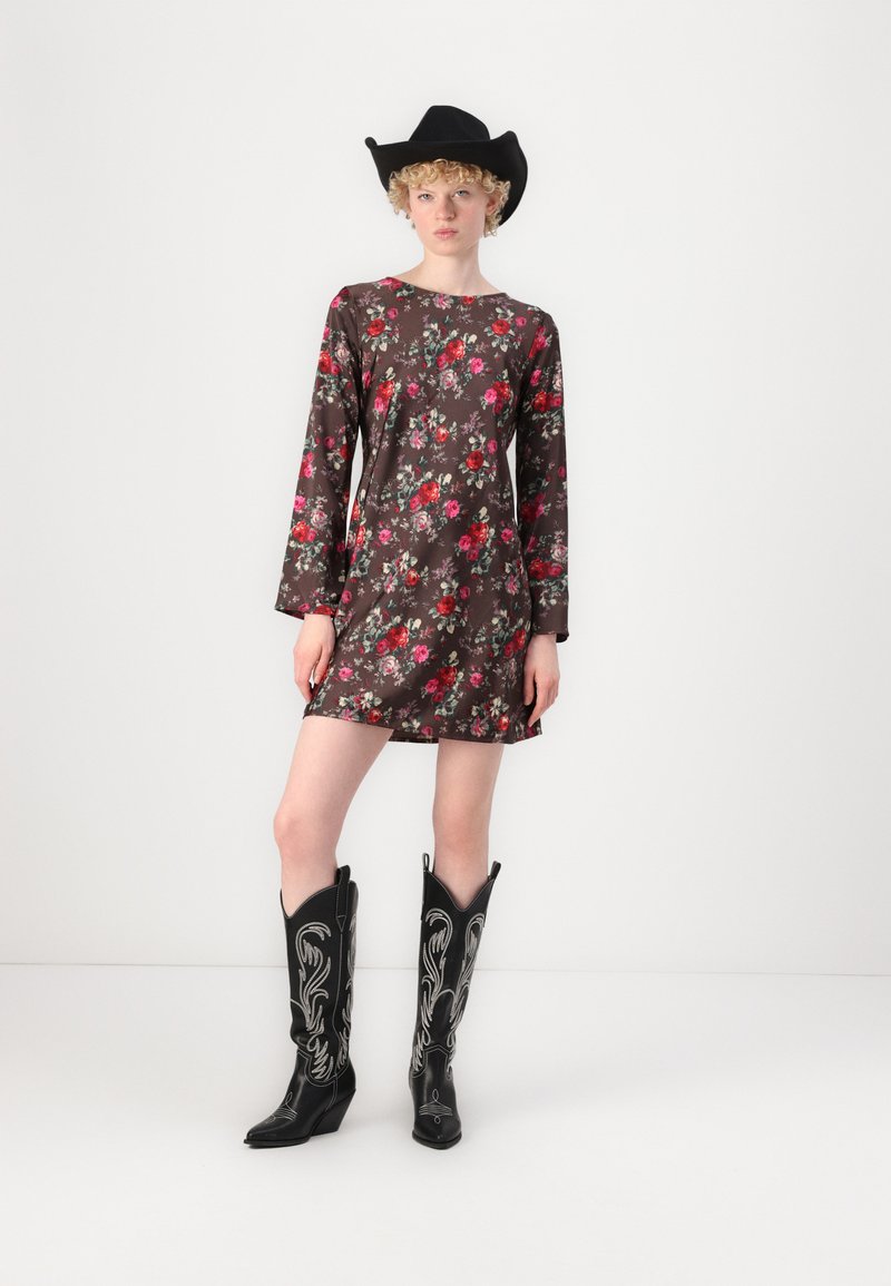 Blumenmuster-Kleid in Dunkelbraun mit langen Ärmeln, kombiniert mit schwarzen Cowboy-Stiefeln mit silberner Stickerei und einem schwarzen Cowboyhut.