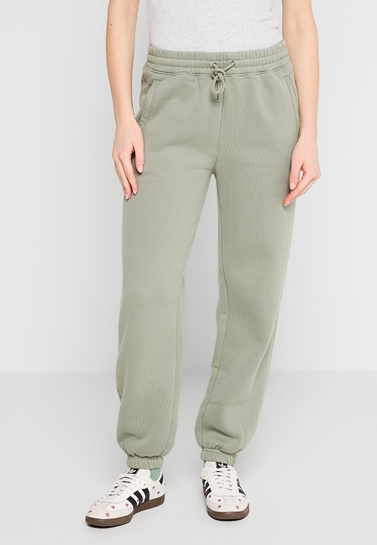 Helle olivgrüne Jogginghose aus weichem Material, mit einem elastischen Bund mit Kordelzug, seitlichen Taschen und ribbeligen Säumen.