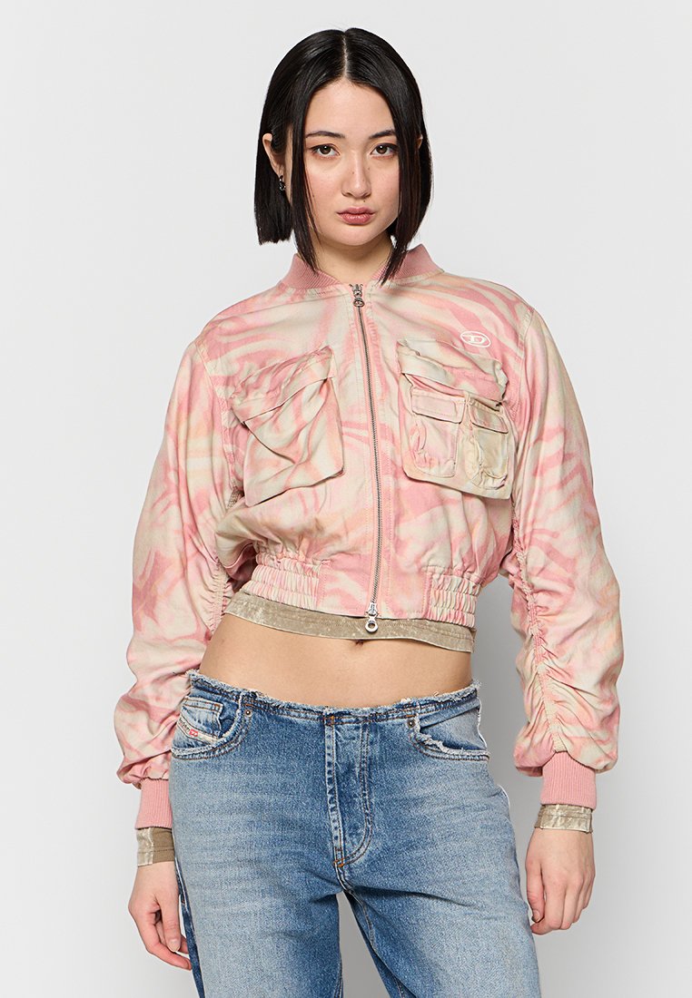 Mit einem Marmor-Muster bedruckte, taillierte Bomberjacke in Pink, ausgestattet mit zwei Brusttaschen sowie elastischen Bündchen und Saum, kombiniert mit blauen Jeans.
