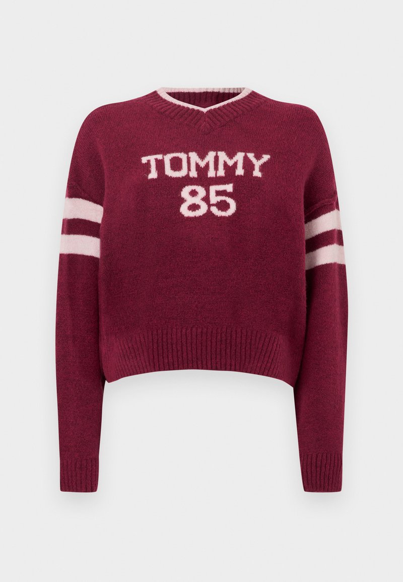 Bordeauxroter kurzer Pullover mit V-Ausschnitt, versehen mit weißer "TOMMY 85" Beschriftung und gestreiften weißen Akzenten an den Ärmeln. Weiche Strickstruktur.