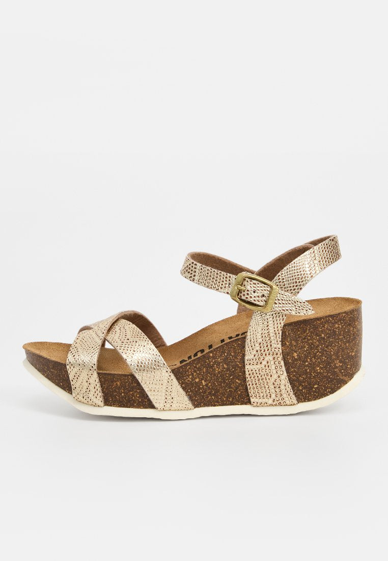 Goldfarbene Kunstleder-Wedge-Sandale mit überkreuzten Riemen, verstellbarem Schnallenverschluss und einer strukturierten Korksohle. Leichtes und unterstützendes Design.
