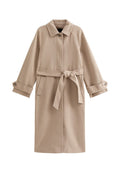 Beiger Trenchcoat mit schlankem Design, Taillengürtel und langen Ärmeln. Verfügt über Seitentaschen und einen leicht strukturierten Kragen.