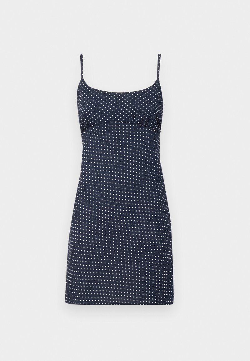 Marineblaues Kleid mit weißen Polka-Dots, das dünne verstellbare Träger und ein tailliertes Oberteil hat, das am Saum leicht ausgestellt ist.