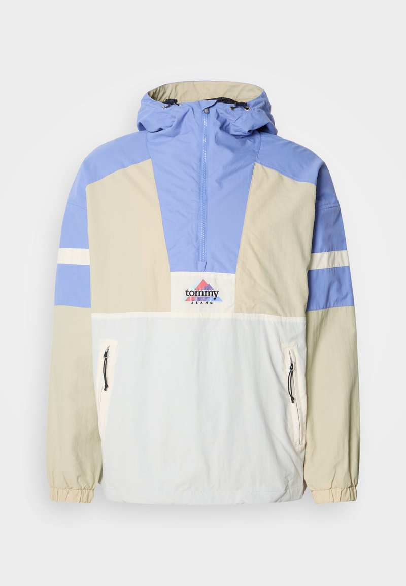 Pullover-Jacke in Blockfarben in Hellblau, Creme und Weiß. Mit Kapuze, halbem Reißverschluss vorne und Reißverschlusstaschen. Logo auf der Brust.