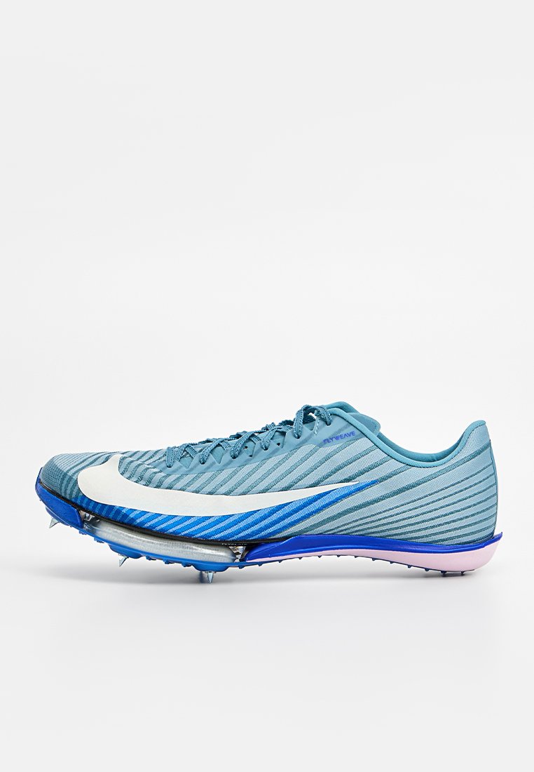 Hellblaue Sportschuhe mit einer strukturierten Oberseite, weißem Swoosh und lilanen Akzenten. Sie verfügen über eine verlängerte Zehenpartie und vier Metallspikes für besseren Halt.