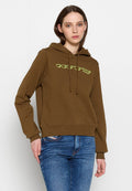 Brauner Kapuzenpullover mit lockerer Passform, versehen mit einem neongrünen Logo auf der Brust sowie gerippten Bündchen und Saum. Kombiniert mit blauen Jeans.
