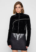 Schwarze Samt-Cropped-Jacke mit hohem Kragen, Frontreißverschluss und kontrastierenden weißen Paspeln. Mit langen Ärmeln und einer weichen Textur.