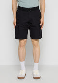 Mann trägt schwarze Cargo-Shorts mit Seitentaschen, einen schwarzen Gürtel, weiße Socken und weiße Turnschuhe, steht vor einem schlichten hellen Hintergrund.