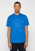 Blaues Baumwoll-T-Shirt mit kurzen Ärmeln, Rundhalsausschnitt und einem strukturierten Druck mit den Worten „DENIM DIVISION“ und „DIESEL 78“ in kontrastierender Farbe.
