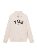 Helle beige Langarm-Polo mit Kragen, das einen großen schwarzen "YALE"-Druck und drei braune Knöpfe aufweist. Hergestellt aus weichem Baumwollmischgewebe.