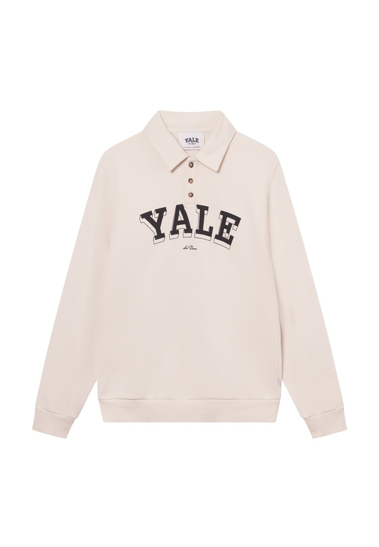 Helle beige Langarm-Polo mit Kragen, das einen großen schwarzen "YALE"-Druck und drei braune Knöpfe aufweist. Hergestellt aus weichem Baumwollmischgewebe.