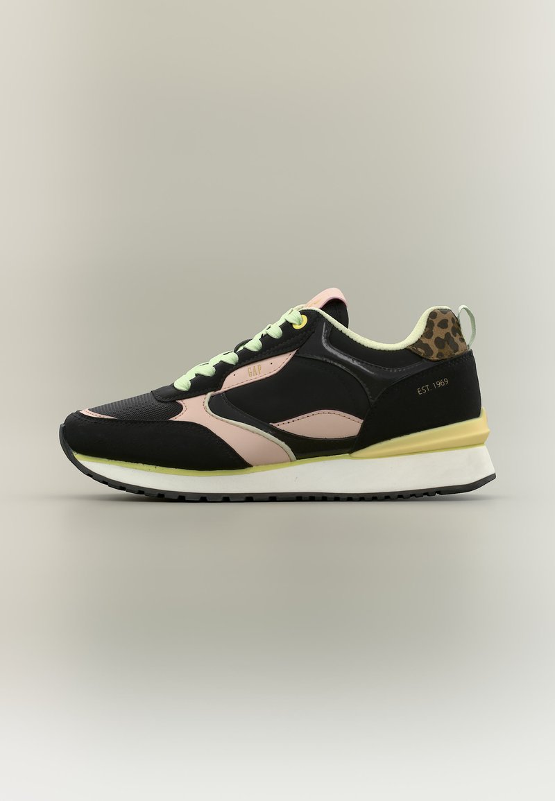 Schwarz-pinker Sneaker mit hellgrünen Schnürsenkeln, Leopardenmuster an der Ferse und weißer Sohle vor neutralem Hintergrund.