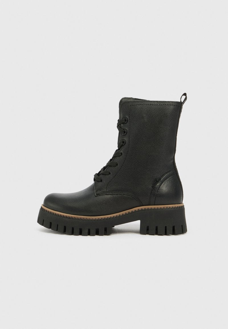 Schwarze Leder Schnürstiefel im Kampfstil mit grobprofilierter Sohle und Ziehlasche auf einfarbigem hellen Hintergrund, Seitenansicht.