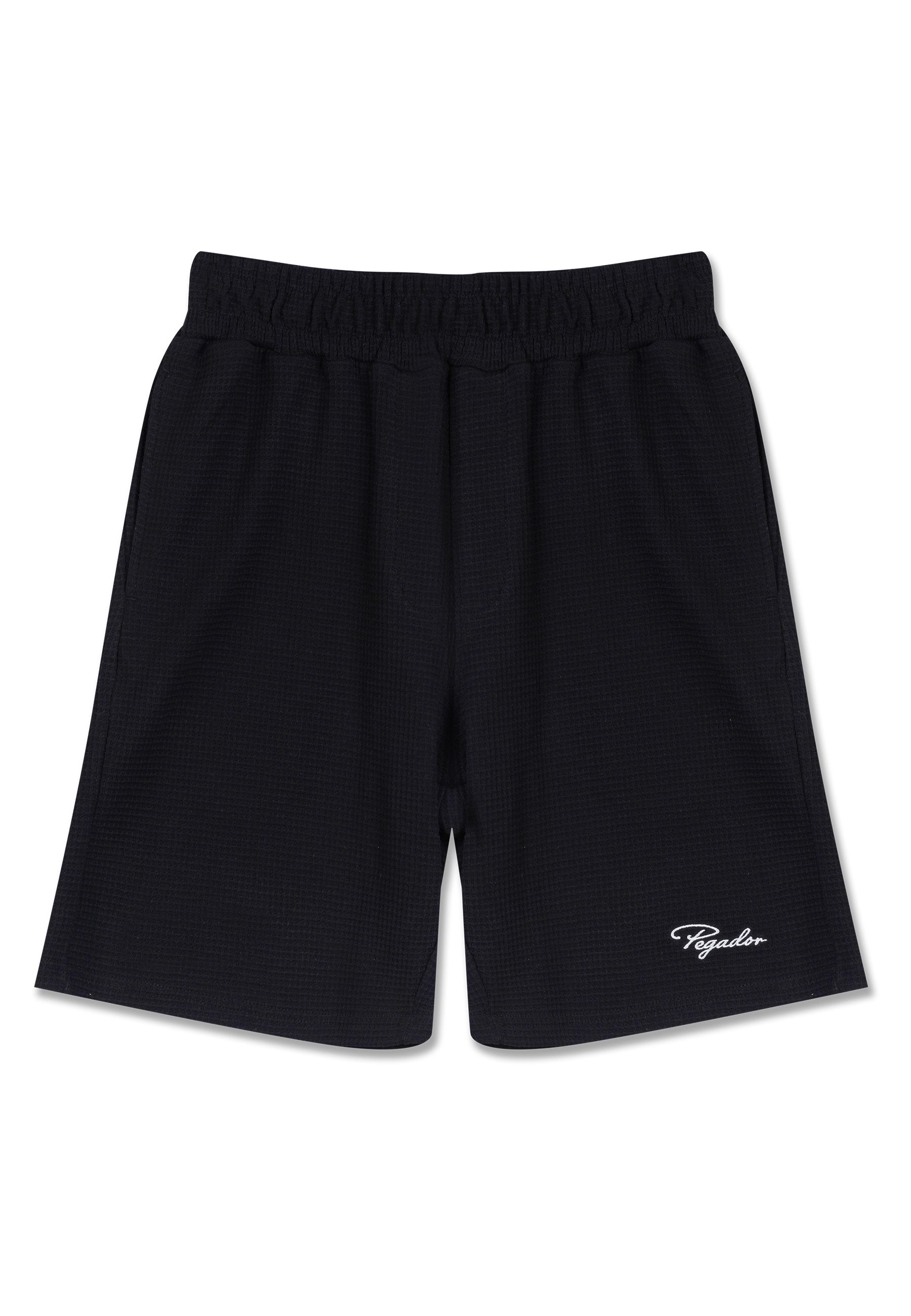 Schwarze Sportshorts mit elastischem Bund, strukturiertem Stoff und einem weißen Logodetail am unteren linken Bein.