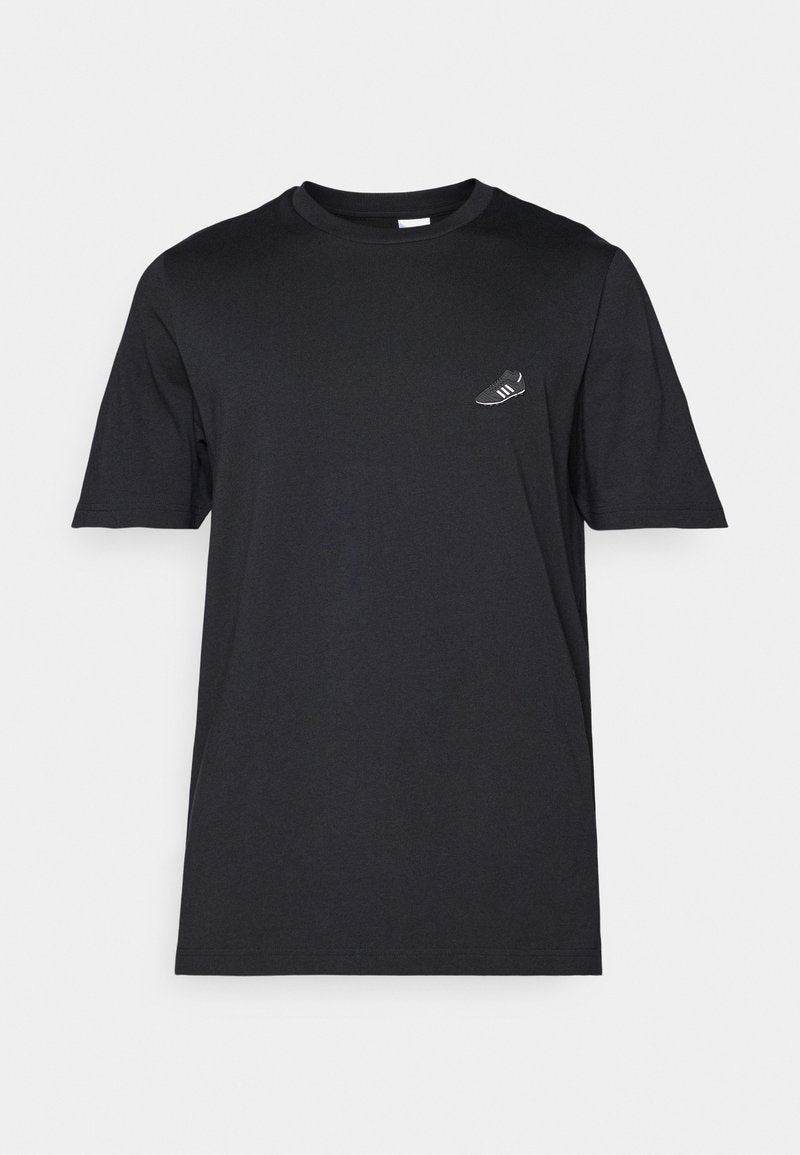 Schwarzes Baumwoll-T-Shirt mit Rundhalsausschnitt, kurzen Ärmeln und einem kleinen weißen Sneaker-Graphic auf der linken Brust. Weicher Stoff, normale Passform.