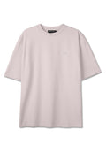 Hellbeiges, übergroßes T-Shirt mit kurzen Ärmeln, rundem Ausschnitt und kleinem weißem Grafiklogo auf der linken Brust.