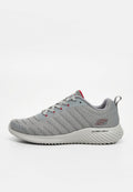 Leichter grauer Sportschuh mit Mesh-Obermaterial, weißer gerippter Sohle, Schnürverschluss, roten Akzenten und Zuglasche hinten.