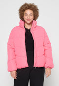 Rosa Puffjacke mit gestepptem Design, Reißverschluss, hohem Kragen und elastischen Bündchen. Tragen über einem schwarzen Rippoberteil mit lässigem Schnitt.