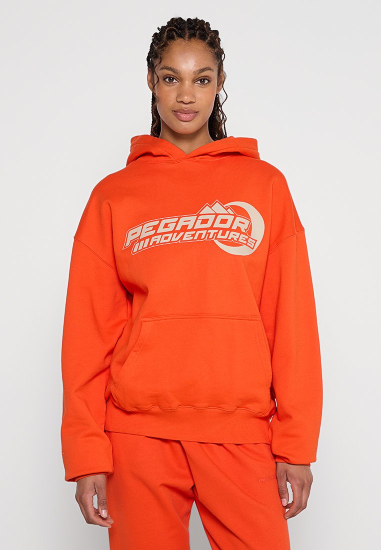 Orangener Hoodie aus Baumwollmischgewebe, mit einer Fronttasche, Kordelzugkapuze und bedrucktem "PEGADOR ADVENTURES"-Logo.