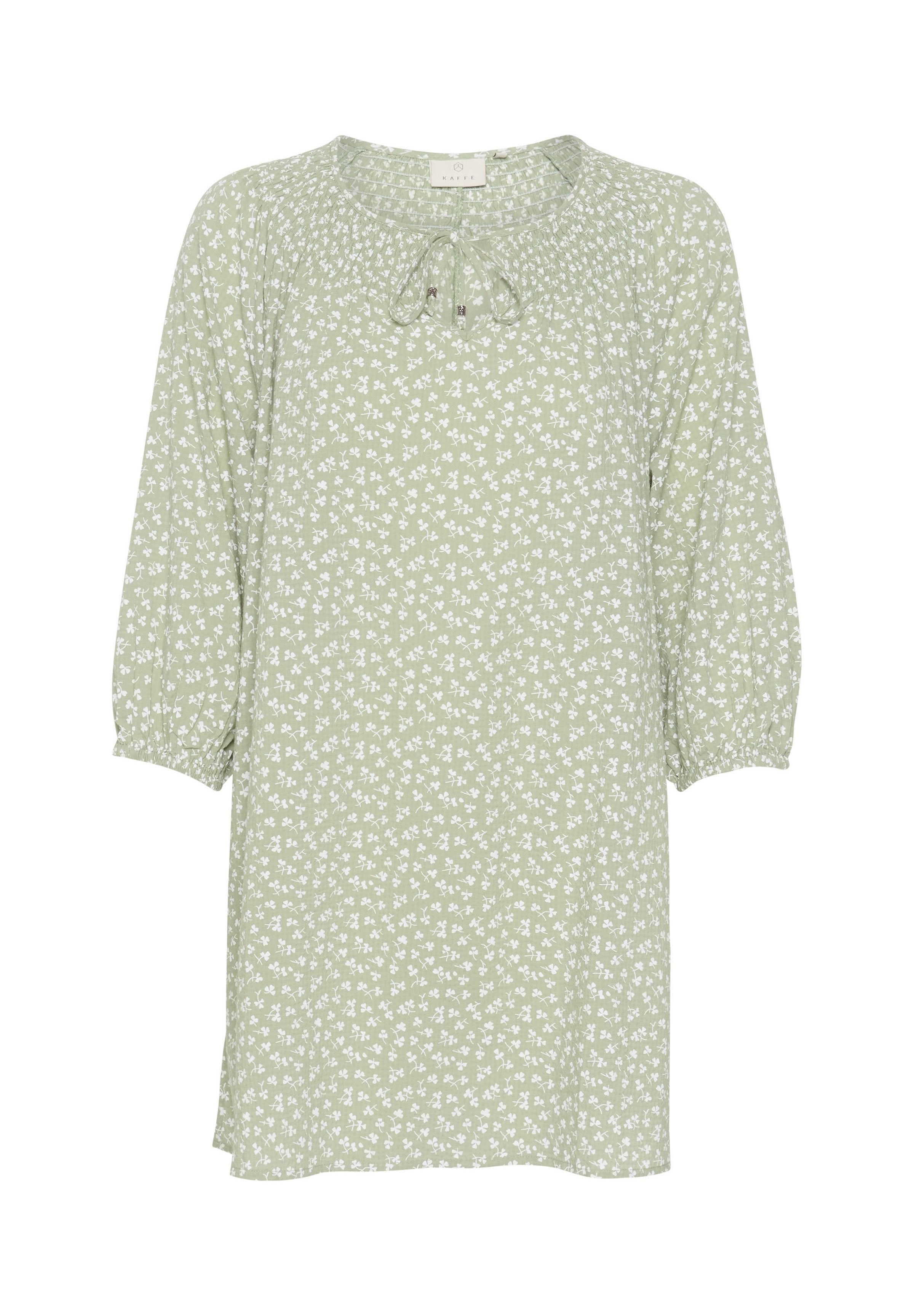Hellgrüne Bluse mit weißem Blumenmuster, rundem Ausschnitt und verstellbarem Bindeband. Mit 3/4 Puffärmeln und lockerer Passform. Weicher Stoff.
