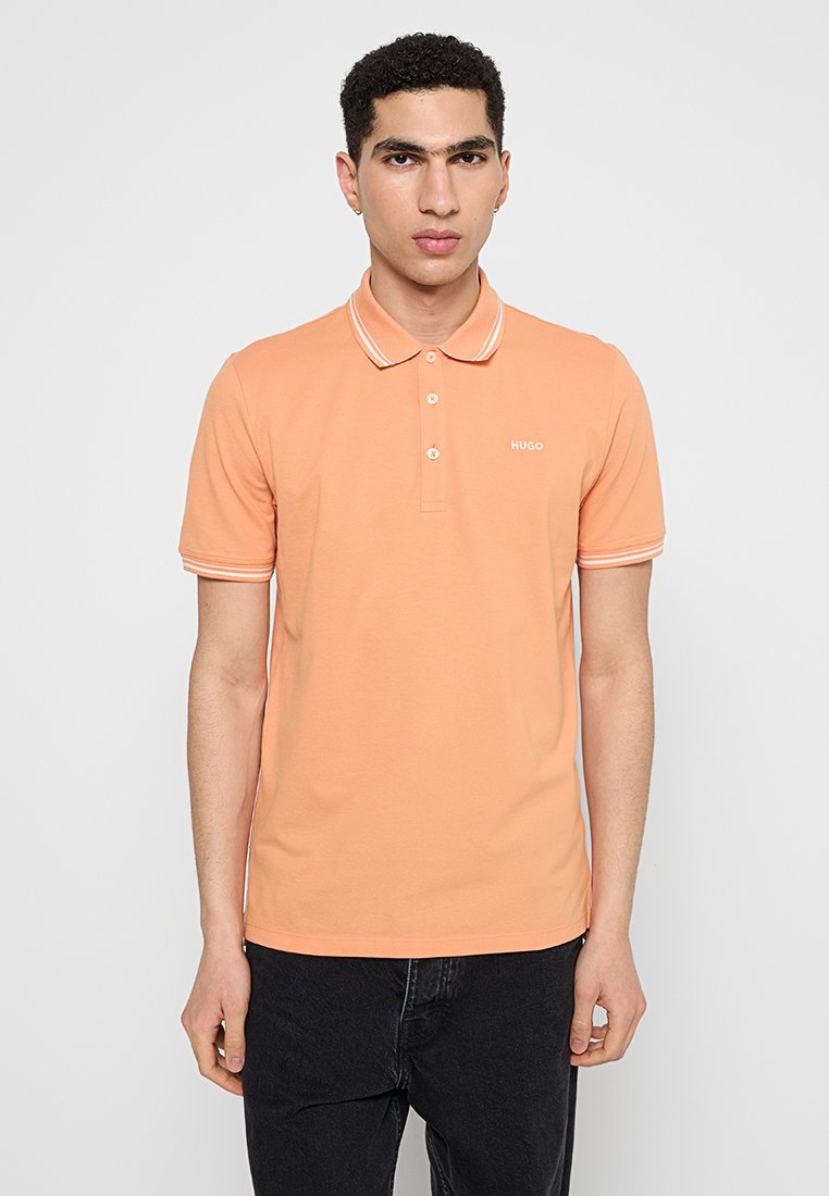 Polohemd aus leichtem orangefarbenem Baumwollstoff mit einer Knopfleiste mit drei Knöpfen, kontrastierenden weißen Kragenstreifen und einem kleinen Logo auf der Brust.