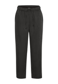 Schwarze, elastische Hosen mit einem Kordelzug. Hergestellt aus einem glatten, weichen Stoff. Knöchellang mit einer lässigen Passform und ohne sichtbare Muster.