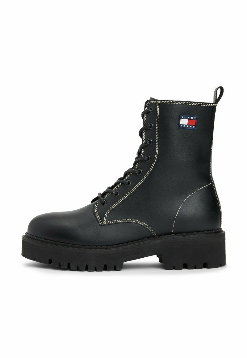 Schwarze Leder-Schnürstiefel mit dicker Sohle, weißen Nähten, Zuglasche und Tommy Jeans-Logo-Patch an der Seite.