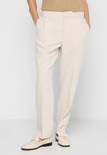 Beige maßgeschneiderte Hose mit geradem Schnitt, vorderen Taschen und glatter Oberfläche, kombiniert mit hellen Loafers.