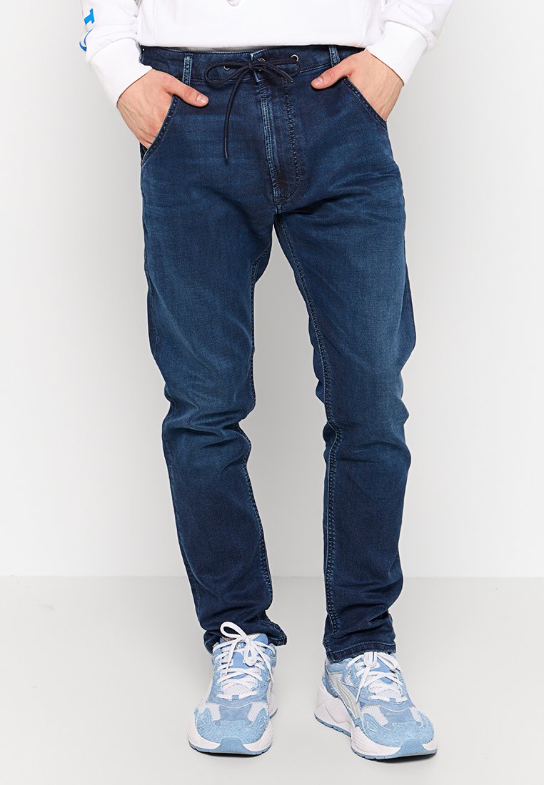 Dunkelblaue Denim-Jogger-Hosen im Stil mit elastischem Bund, vorderen Taschen und tapered Beinform. Weicher, strukturiert Stoff.