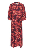 Blumenmuster-Kleid mit kurzen Puffärmeln, Kragen und durchgehender Knopfleiste. Die Farben umfassen dunkles Rot und leuchtende Korallenakzente.