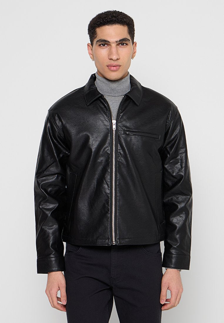 Schwarze Lederjacke mit Frontreißverschluss, spitzem Kragen, seitlichen Taschen und einer kleinen Brusttasche. Glatte Textur mit tailliertem Design.