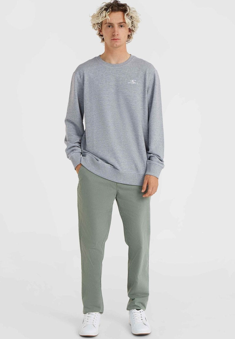 Grauer Langarm-Sweatshirt mit rundem Halsausschnitt und gerippten Bündchen, kombiniert mit hellgrünen Hosen und weißen Sneakern.
