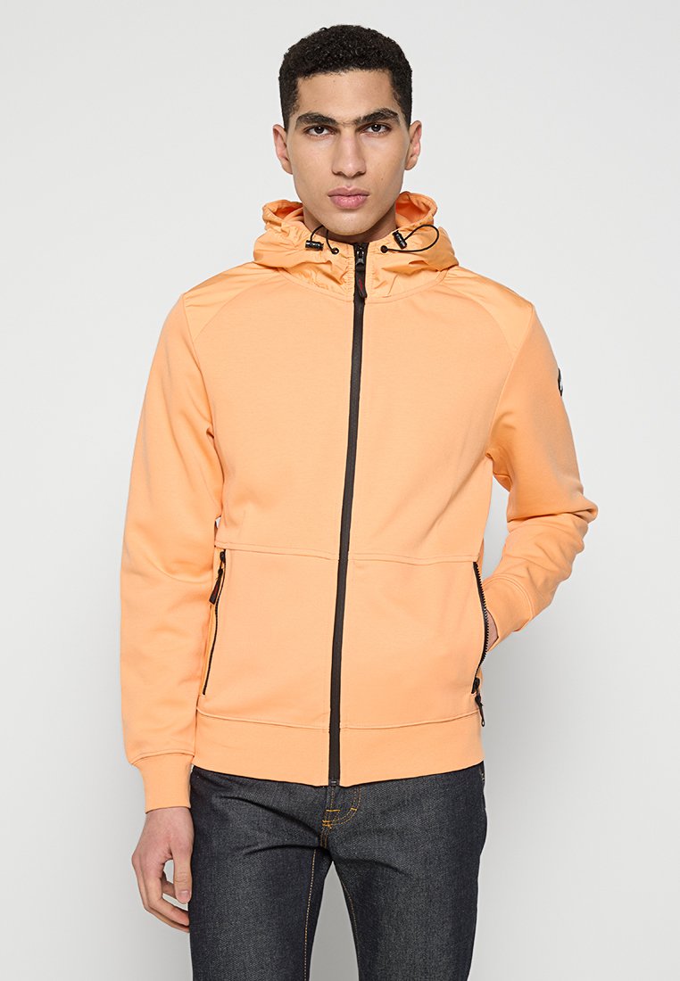 Helle orange Zip-Hoodie mit verstellbarem Kapuzenzug, schwarzem Reißverschluss, seitlichen Taschen und gerippten Bündchen, gefertigt aus einem glatten Material.