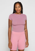 Enganliegendes T-Shirt mit kurzen Ärmeln in Helllila mit Nike-Logo; kombiniert mit hochgeschnittenen, dehnbaren rosa Shorts mit Seitentaschen.