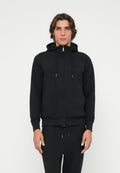Schwarzer Kapuzenpullover mit Reißverschluss, Kapuze, Kordelzug und gerippten Bündchen. Weicher Stoff mit subtiler Textur, kombiniert mit passenden schwarzen Jogginghosen.