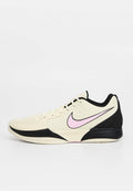 Nike-Sportschuh mit cremefarbenem Mesh-Obermaterial, schwarzen Akzenten, strukturierten Seiten und einem pinkfarbenen Swoosh-Logo. Verfügt über eine gedämpfte Sohle und ein Wellenmuster.
