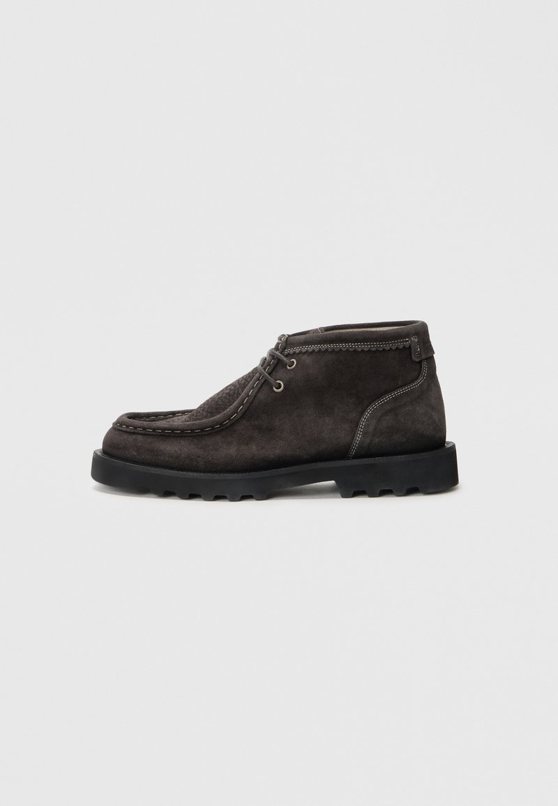 Dunkelgraue Wildleder-Stiefeletten mit einer strukturierten Zehenpartie, Schnürdetails und kontrastierenden Nähten. Mit einer robusten schwarzen Gummisohle.