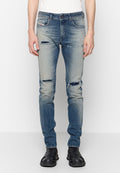 Hellblaue, ausgewaschene Jeans mit Verwaschungen und Rissen an den Oberschenkeln und Knien, kombiniert mit schwarzen Gummislippern.