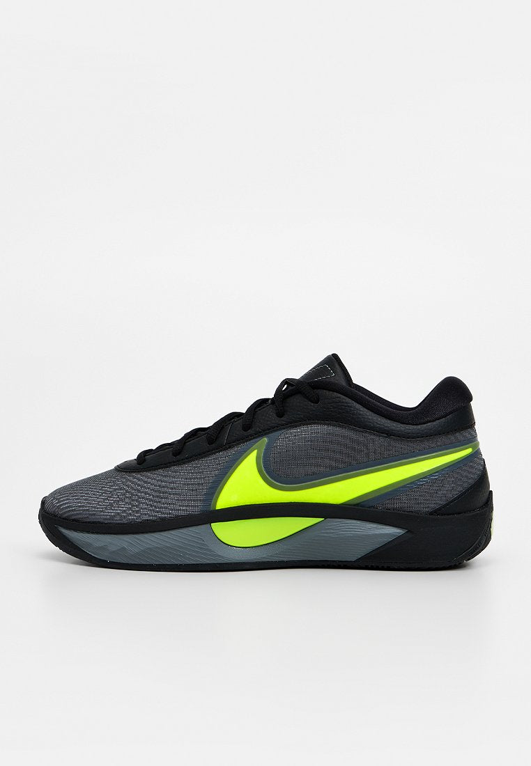 Schwarzer Sportschuh mit einem strukturierten grauen Obermaterial, versehen mit einem leuchtend gelben Nike-Swoosh und schwarzen Schnürsenkeln. Gummisohle mit flachem Profil.