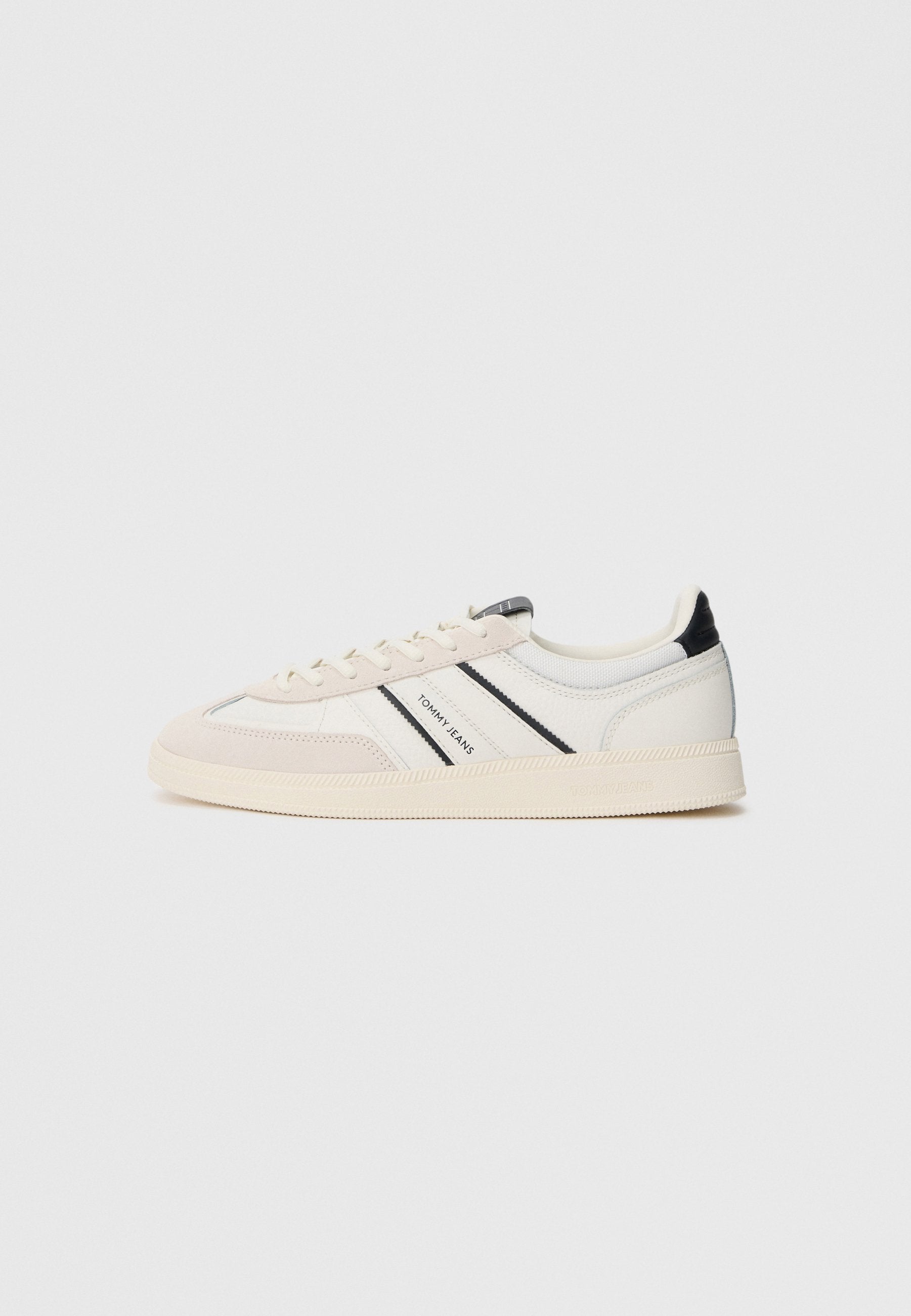 Weiße Sneakers mit beigen Wildlederakzenten, schwarzen und blauen Streifen sowie einer strukturierten Gummisohle. Mit Branding an der Seite und der Zunge.