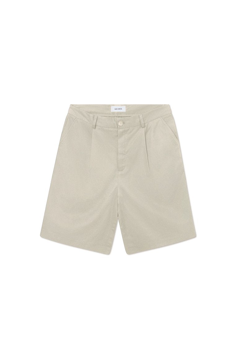 Beige maßgeschneiderte Shorts mit flachem Bund, zwei Seiten Taschen und einem einzelnen Knopfverschluss. Hergestellt aus einem leichten, glatten Stoff.