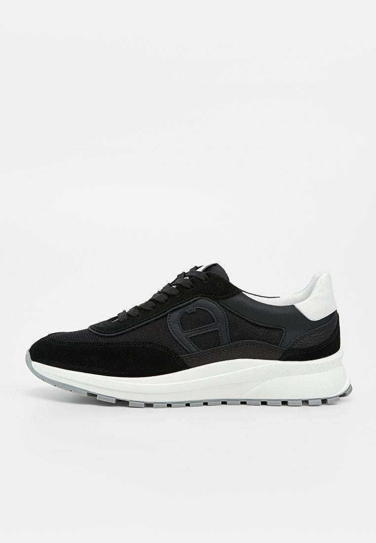 Schwarz-weißer Sneaker mit niedrigem Schaft, Mesh- und Veloursleder-Obermaterial, dicker weißer Sohle und Schnürverschluss, im Profilansicht gezeigt.
