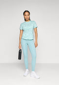 Helles blaues Sport-T-Shirt mit dezentem Muster, kombiniert mit passenden Leggings. Das Model hält eine schwarze Wasserflasche und trägt weiße Sneaker.