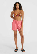 Markierter mehrfarbiger Bikini-Oberteil mit spiralförmigem Muster, kombiniert mit hellrosa elastischen Shorts und schwarzen Slipper-Sandalen. Glatte Textur insgesamt.